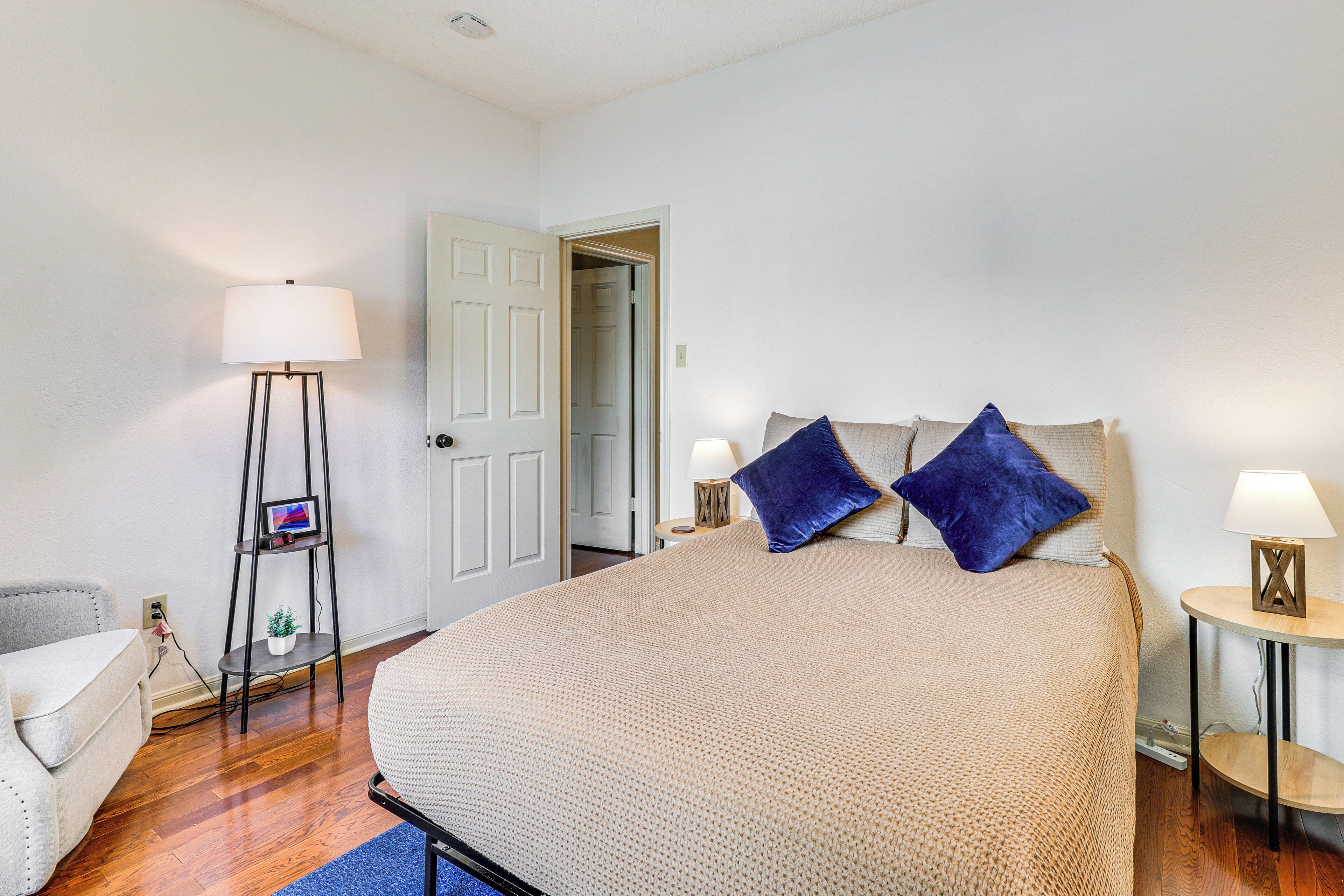 Une chambre à coucher avec un grand lit, une table de chevet avec une lampe, un lampadaire et une chaise.
