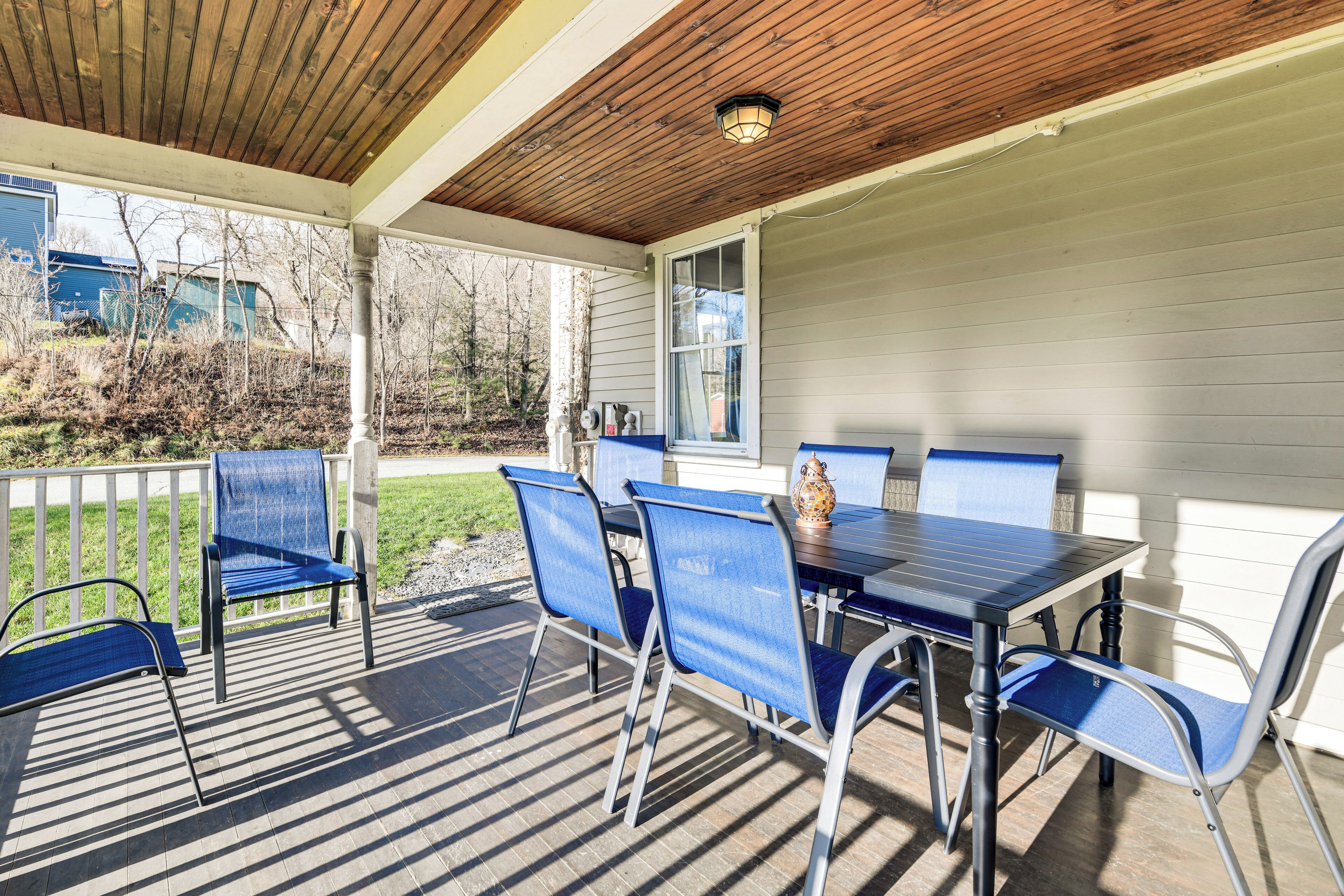A covered patio with a table and chairs, a wooden ceiling, and a view of the backyard.