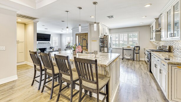 Una cocina amplia con una isla grande, sillas de madera y armarios blancos.