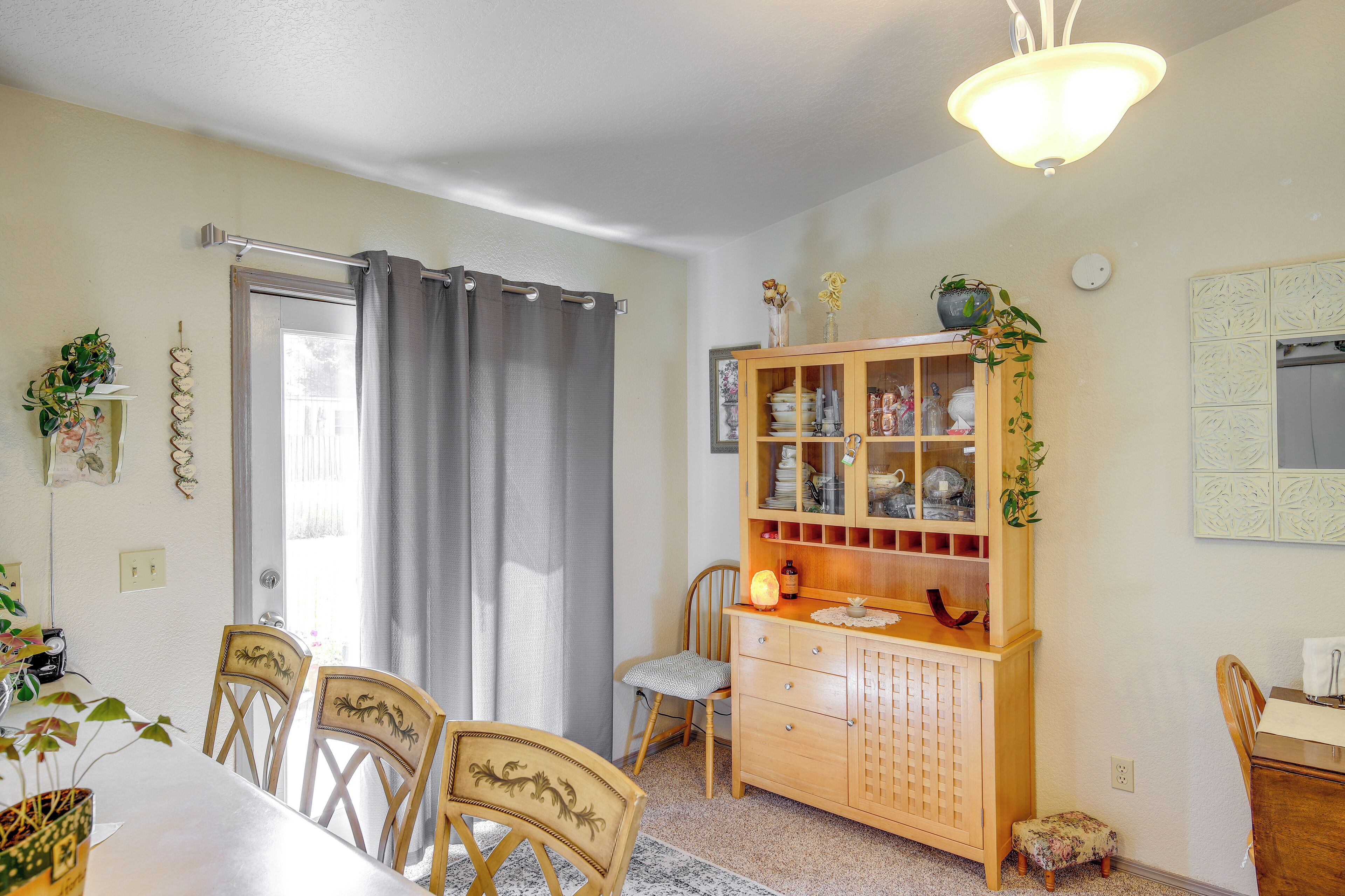 A dining area with a table, chairs, a wooden cabinet with glass doors, and a ceiling light fixture.