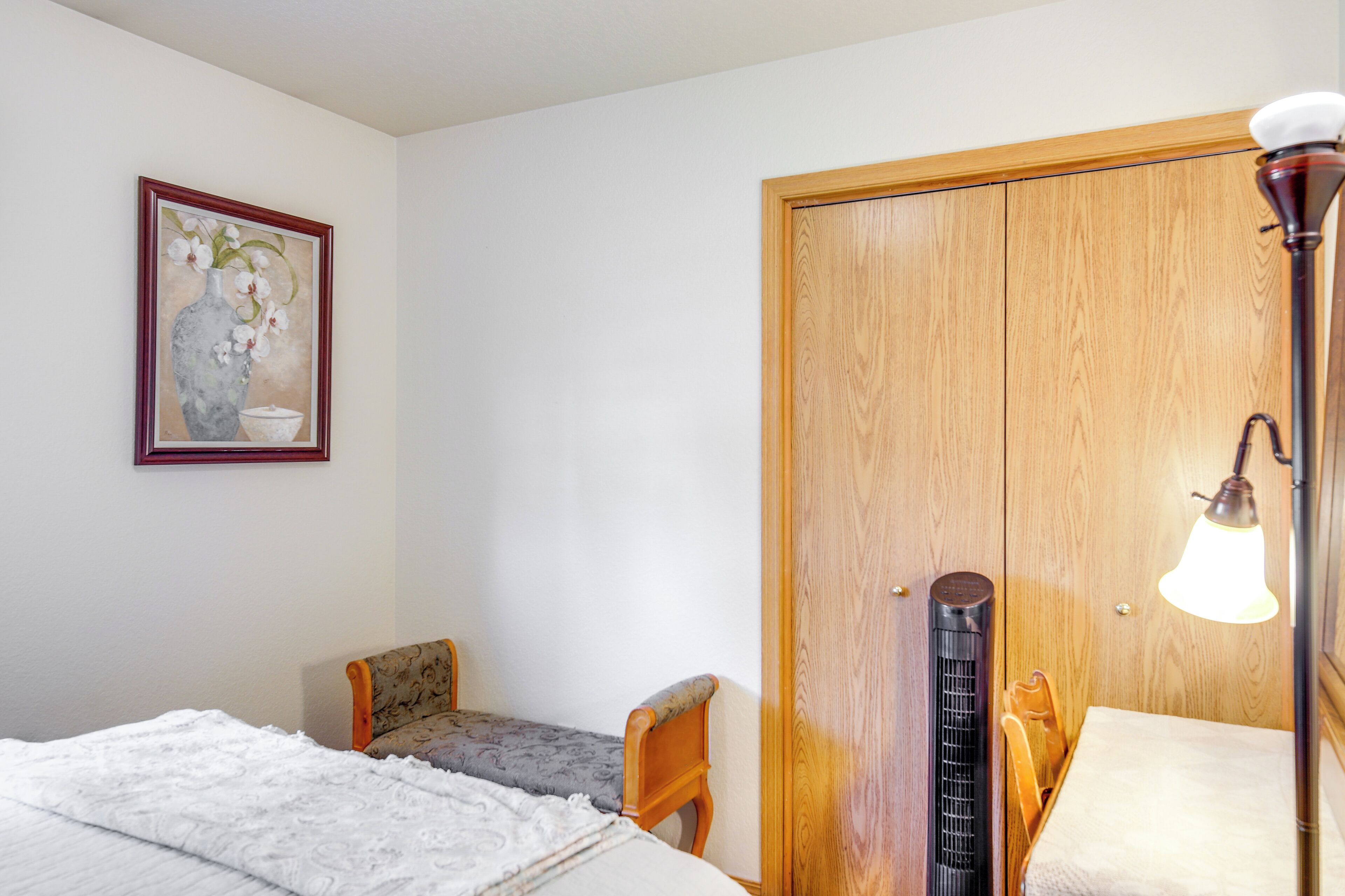 Une chambre à coucher comprenant un lit, une chaise, une armoire en bois, un radiateur et une lampe.
