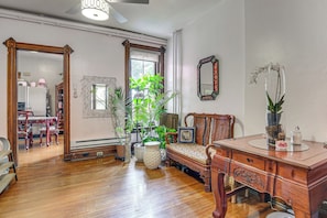 Una habitación amplia con suelo de madera, un banco de madera, una mesa con cubierta de vidrio y una variedad de plantas en macetas.