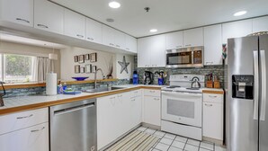 A modern kitchen with white cabinets, stainless steel appliances, and a tiled backsplash. - Holmes Beach Condo Near Anna Maria: Pool Access! (Holmes Beach)