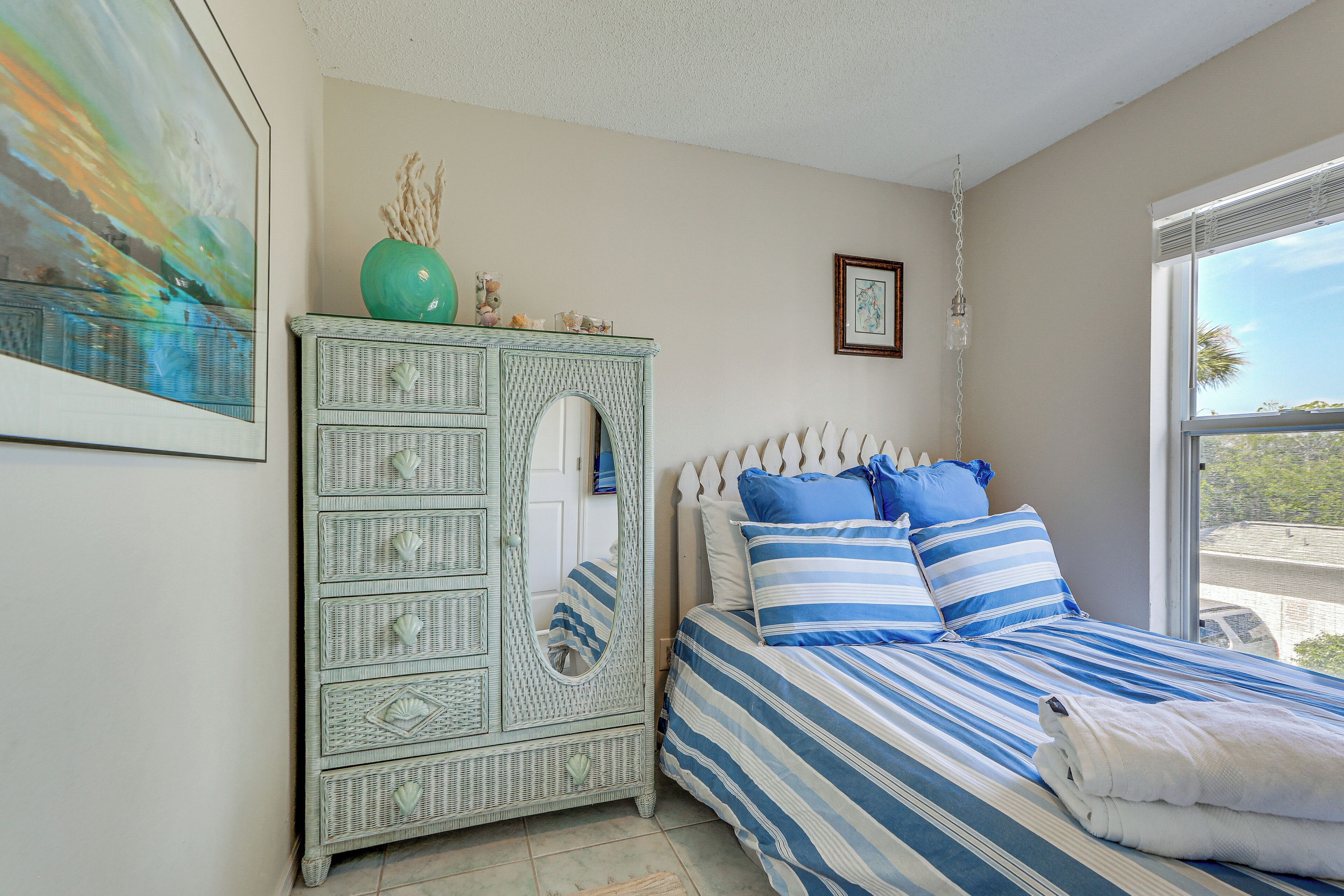 A bedroom with a bed, dresser, and a painting on the wall.