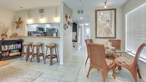 A spacious living area with a kitchen, dining table, and bar stools. - Holmes Beach Condo Near Anna Maria: Pool Access! (Holmes Beach)