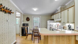 Una cocina con armarios de madera, una isla central y una zona de comedor con sillas.