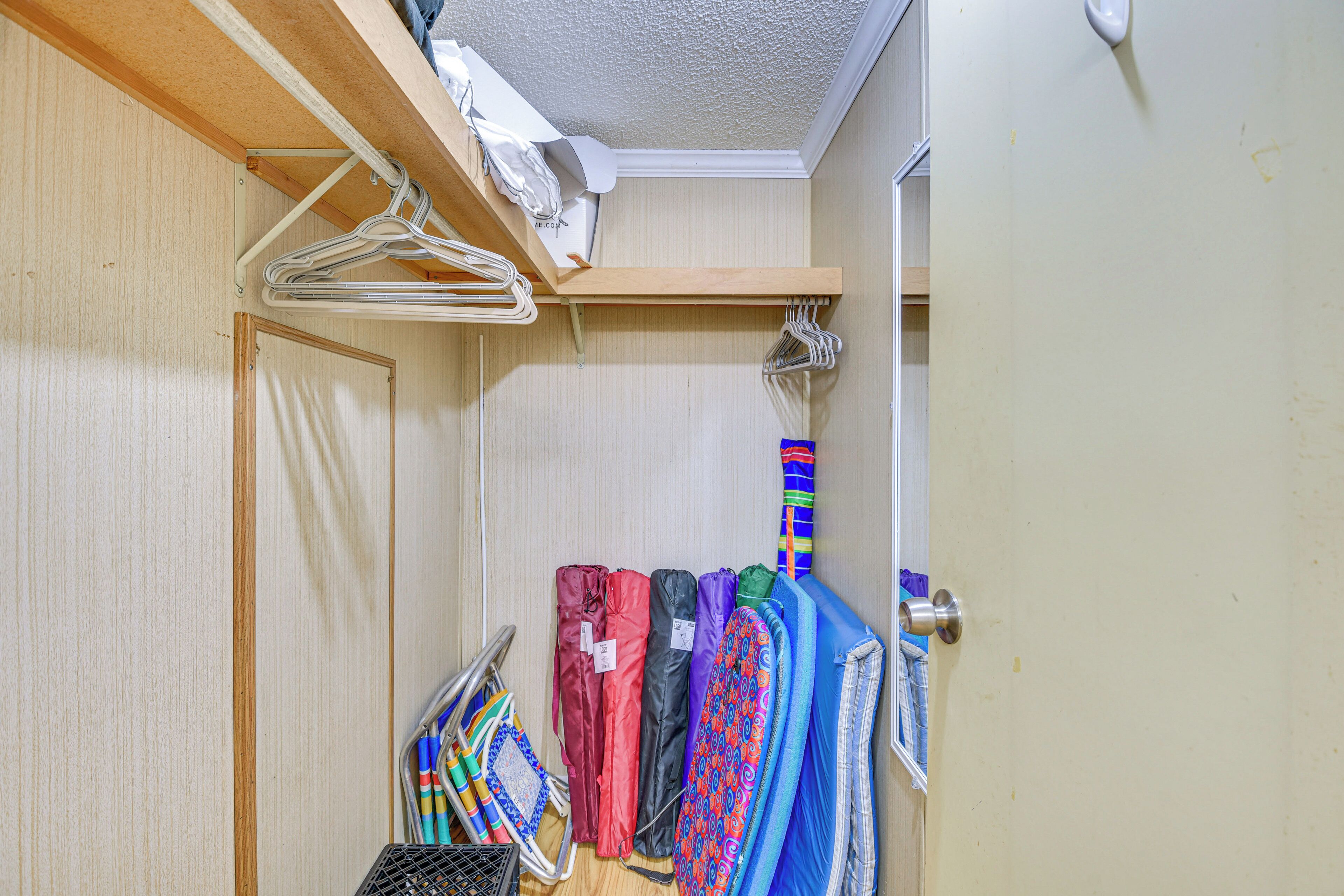 A closet with hanging clothes and a door with a handle.