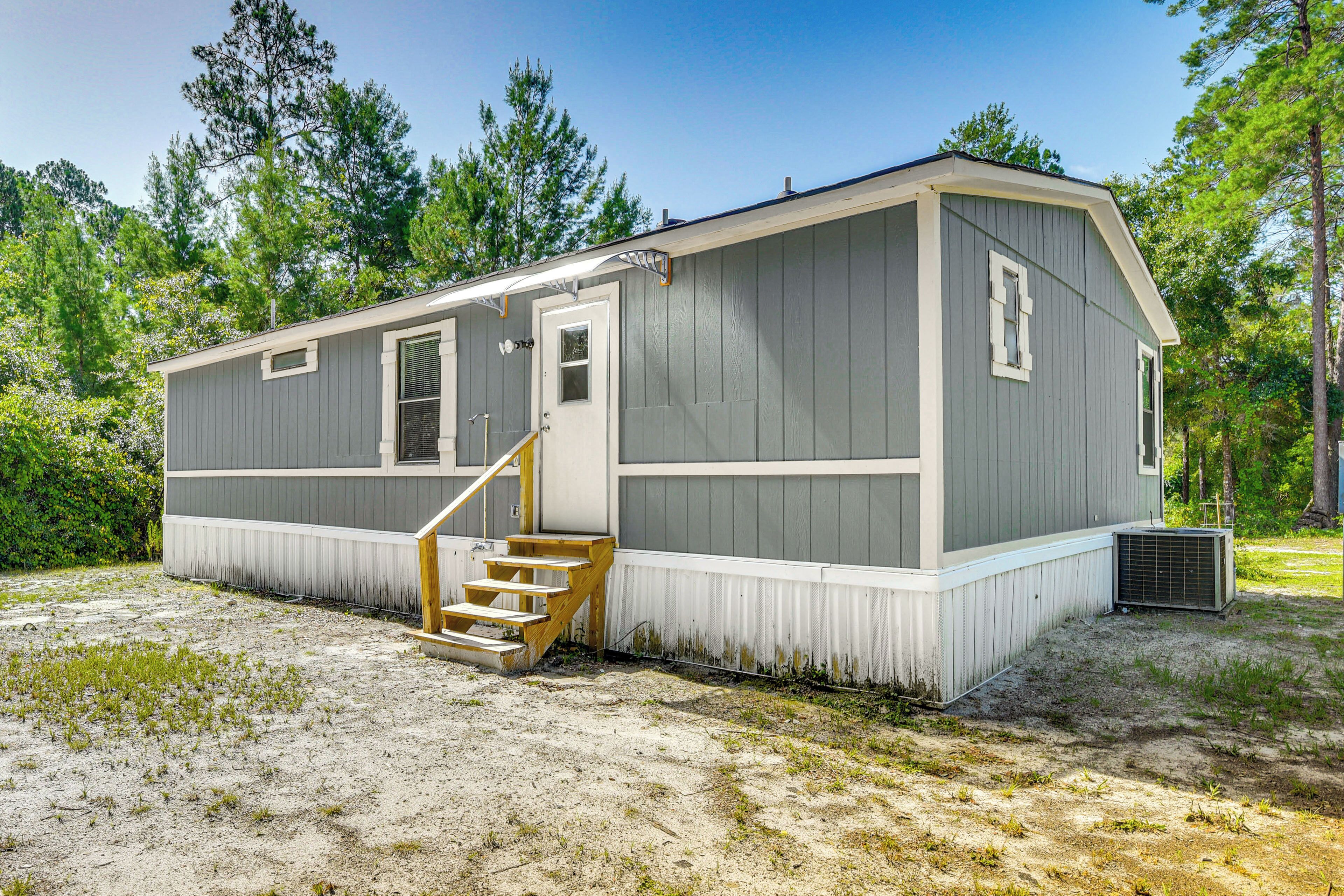 A single-story mobile home with a front porch and a staircase leading to the entrance.