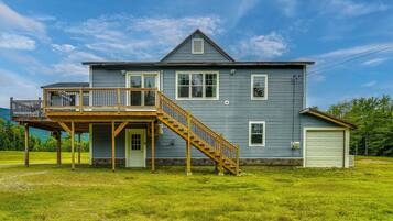 A two-story house with a wooden deck and a staircase leading to the second floor.