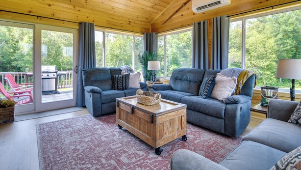 A cozy living room with a wooden ceiling, two sofas, a coffee table, and a view of the outdoors through large windows. - Mountain-view Maine Cabin: Ski, Hike & Bike! (Strong)