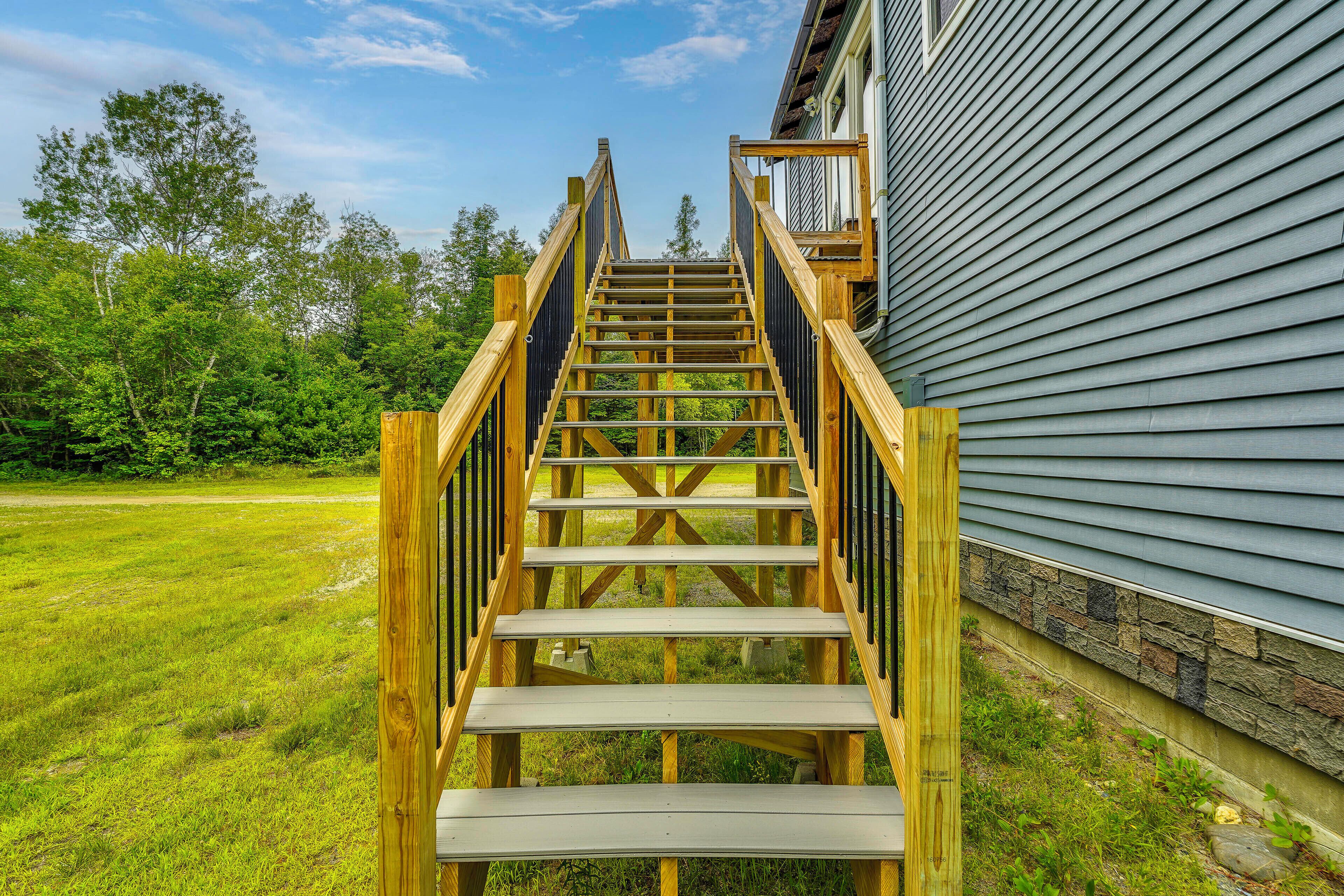 A wooden staircase leading to a house with a stone foundation.