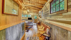 L’intérieur d’une cabane en rondins, avec un plafond en bois, un canapé, un téléviseur et une statue.