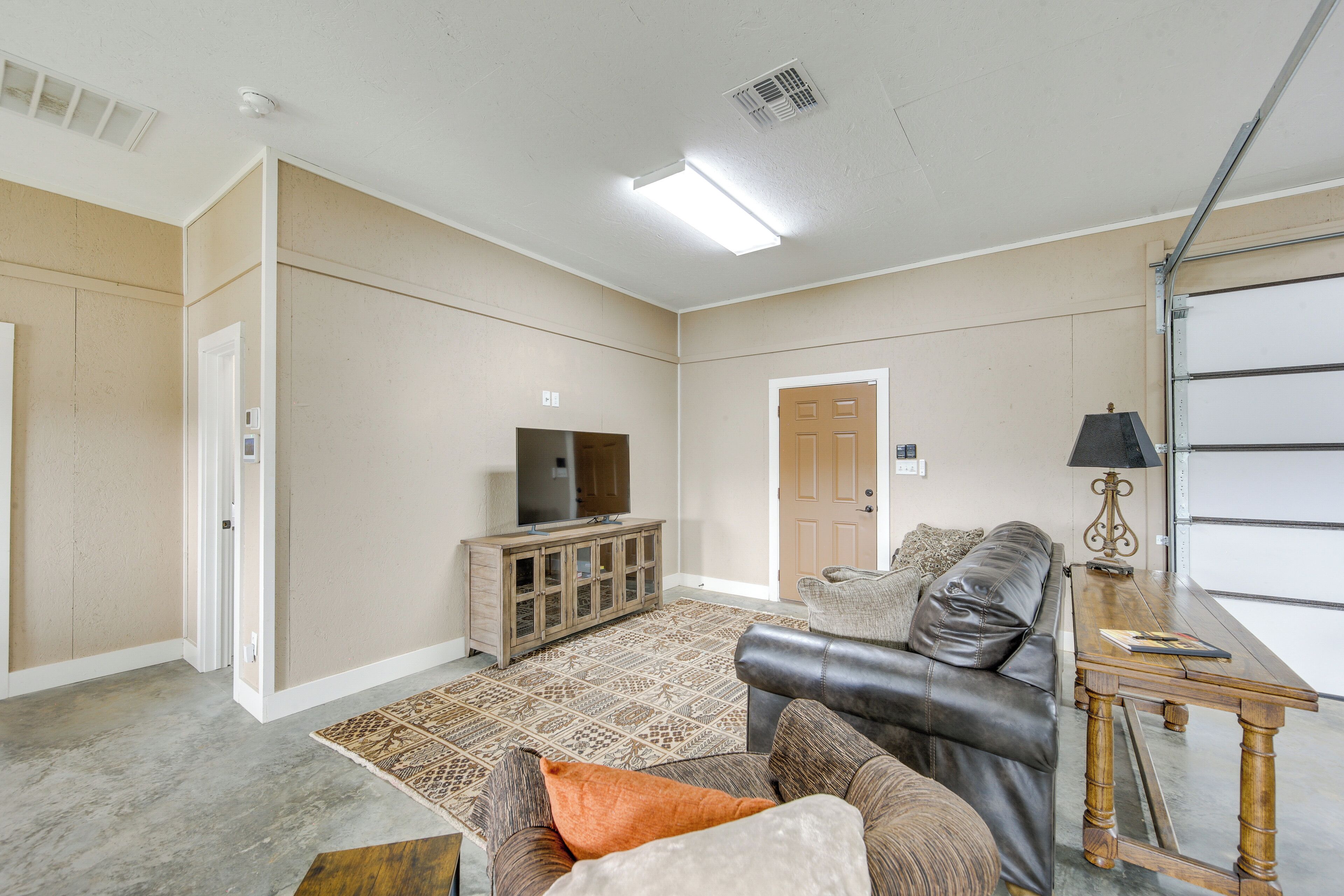 A spacious living room with a leather couch, a wooden coffee table, and a flat-screen TV on a cabinet.
