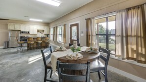 A spacious kitchen with a dining area, featuring a large island, bar stools, and a view through the windows. - Quiet Lake Gladewater Getaway w/ Dock & Kayaks! (Gladewater)