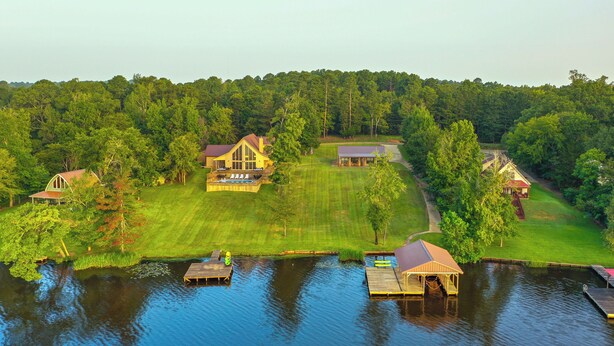 A lakeside property with multiple buildings, docks, and a well-maintained lawn. - Quiet Lake Gladewater Getaway w/ Dock & Kayaks! (Gladewater)