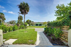 A residential driveway leading to a house with a green garage, surrounded by well-maintained lawns and a variety of trees. - By Fort Pierce Inlet State Park! Condo w/ Yard (Fort Pierce)