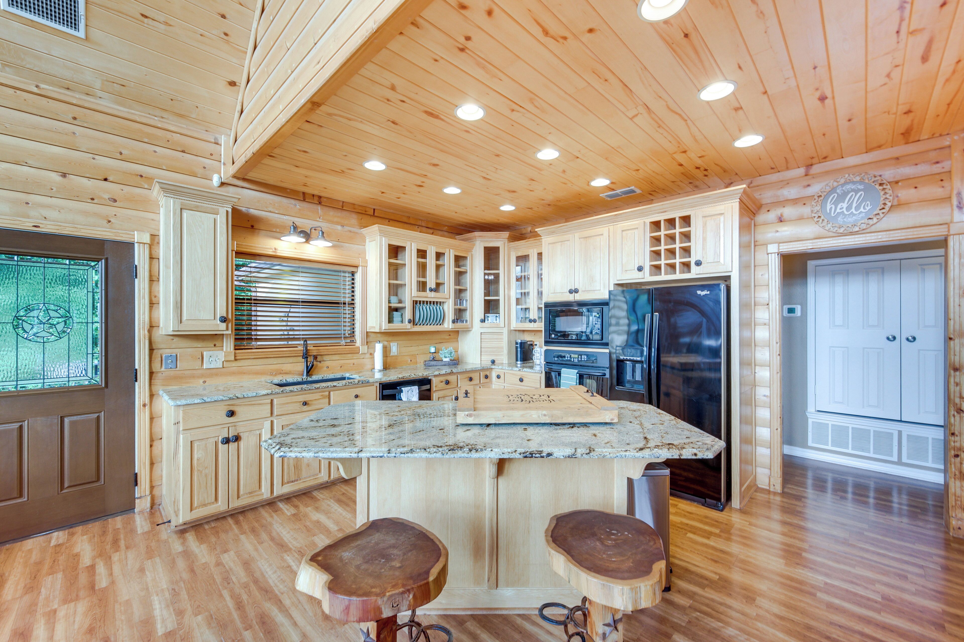A spacious kitchen with wooden cabinets, a granite countertop, and a central island with stools.