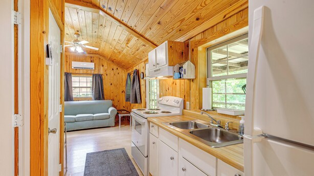 A compact kitchen with wooden cabinets, a stove, and a sink. - Serene Clarkson Cabin ~ 4 Mi to Nolin Lake Access! (Clarkson)