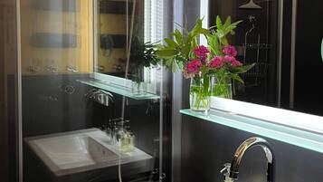 Ein modernes Badezimmer mit Duschkabine aus Glas, einem weißen Waschbecken und einem Spiegel darüber.