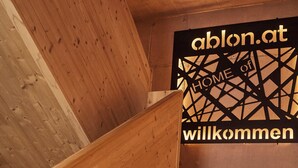 A wooden staircase with a sign reading "ablon.at HOME" and "willkommen" in a modern interior. - Chalet Ablon (Saalbach-Hinterglemm)