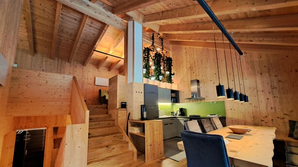 A wooden interior with a staircase, kitchen, and dining area. - Chalet Ablon (Saalbach-Hinterglemm)