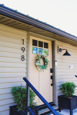A house with the number 198 on the door, a wreath, and two potted plants.
