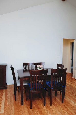A dining area with a wooden table and chairs, a small potted plant, and a doorway leading to another room.
