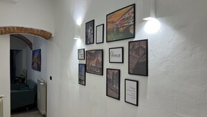 En hall med inramade bilder av italienska städer, en tegelbåge och ett element.