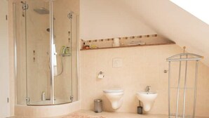 Une salle de bain moderne avec une douche à parois de verre, des toilettes, un bidet et un lavabo.