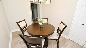 A dining area with a round wooden table, four chairs, a vase with flowers, and a hanging light fixture. - 5 min walk to Notre Dame! Modern home (517) (South Bend)