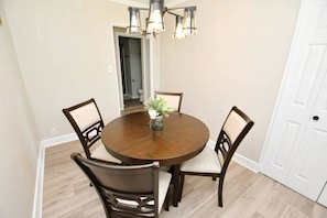 A dining area with a round wooden table, four chairs, a vase with flowers, and a hanging light fixture. - 5 min walk to Notre Dame! Modern home (517) (South Bend)