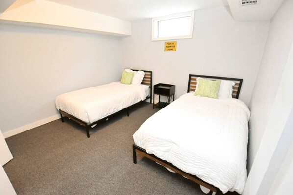 A room with two single beds, a small table, and a window.