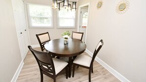 A dining room with a round table, four chairs, a chandelier, and two wall decorations. - 5 min walk to Notre Dame! Modern home (517) (South Bend)