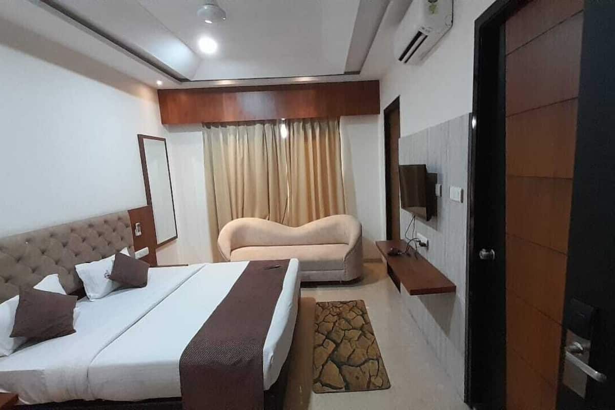 Una habitación de hotel con cama, sofá, televisión y armario.
