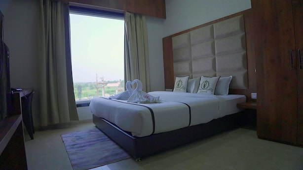 Een hotelkamer met een groot bed, een houten hoofdeinde en uitzicht op het omliggende landschap.