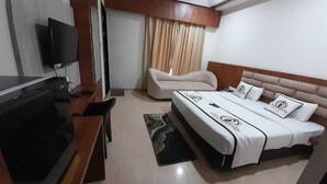 Een hotelkamer met een bed, een televisie, een bureau en een stoel.