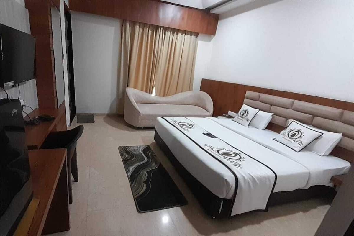 Una habitación de hotel con una cama, televisión, escritorio y una silla.