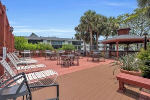 An outdoor patio with multiple barbecue grills, lounge chairs, and tables.