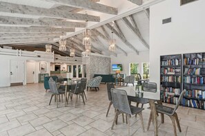 A spacious living area with a high ceiling, exposed beams, and a large bookshelf.