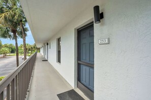 A hotel corridor with a number 253 sign, a blue door, and a view of the street with palm trees.