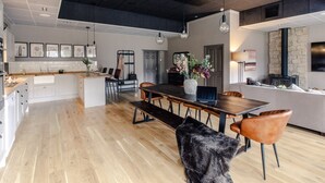 Une cuisine moderne avec des meubles blancs, un plan de travail en bois et un coin repas comprenant un banc et des chaises.