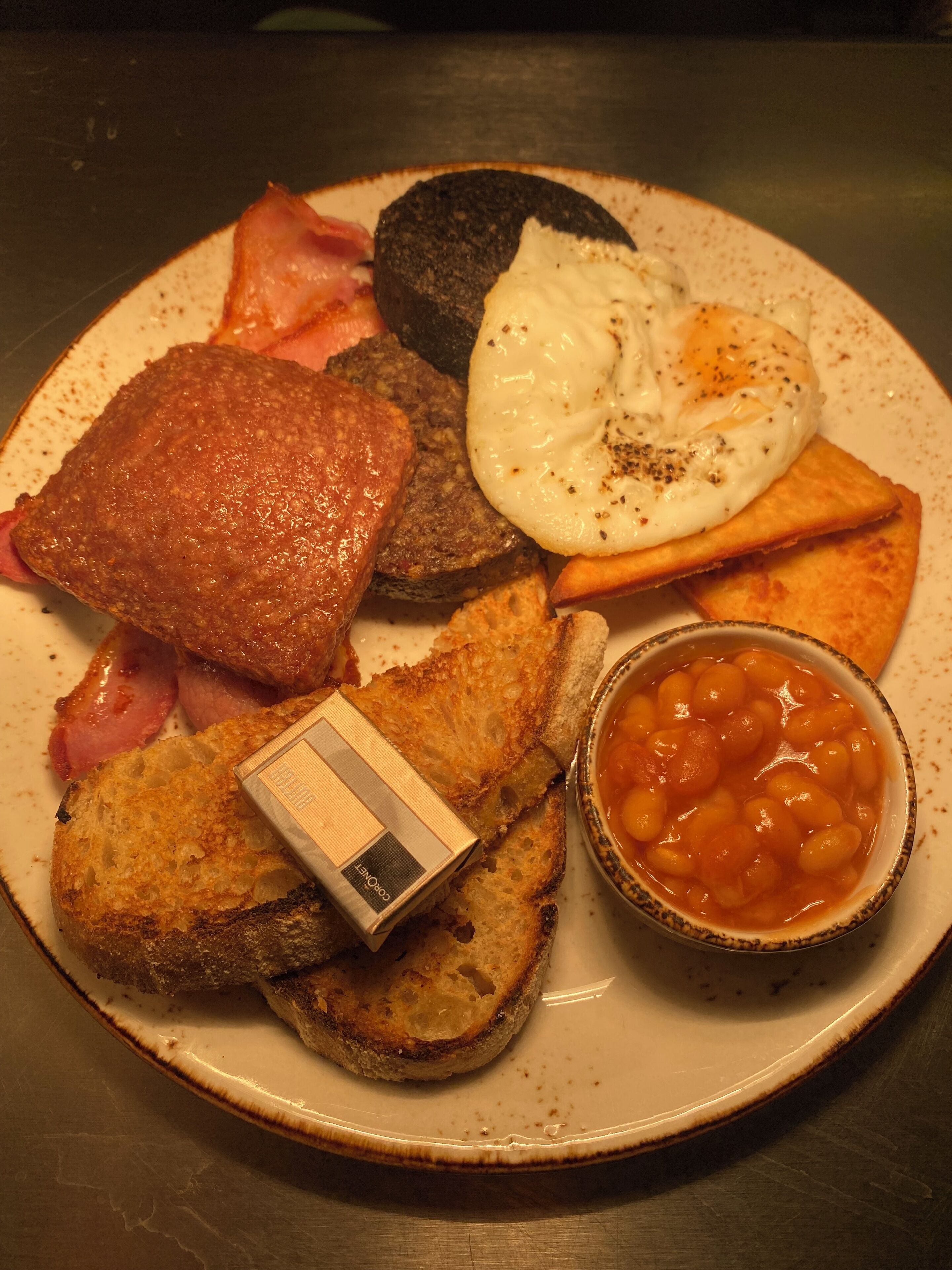 A plate of breakfast food including eggs, bacon, toast, and beans.