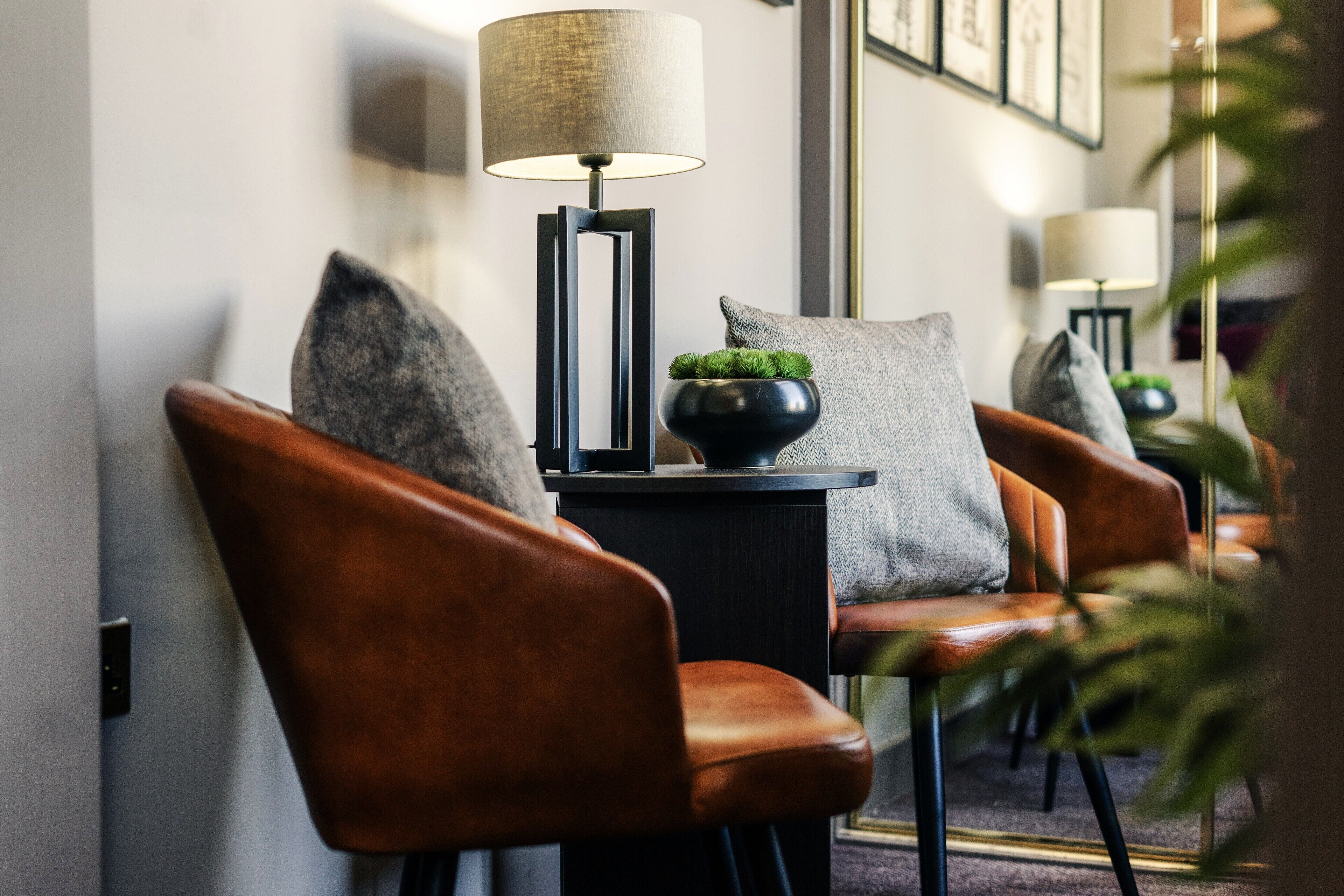A modern interior with leather chairs, a side table with a lamp, and a small plant.