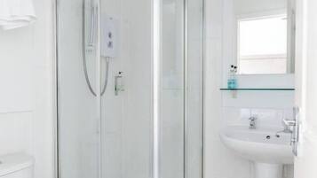 A modern bathroom with a glass-enclosed shower, a white sink, and a toilet.