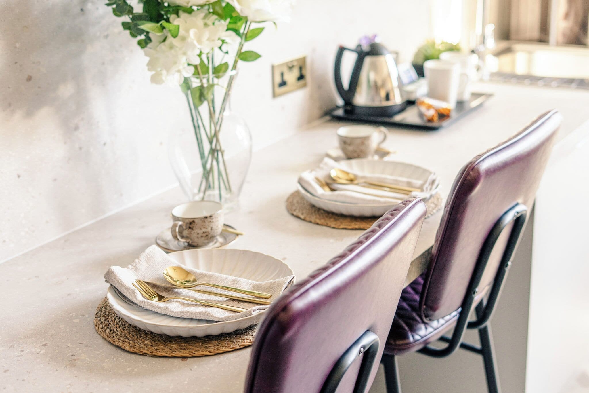 Una mesa de comedor dispuesta con platos, cubiertos y un florero.
