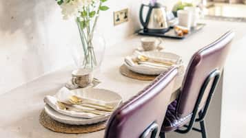 Una mesa de comedor dispuesta con platos, cubiertos y un florero.