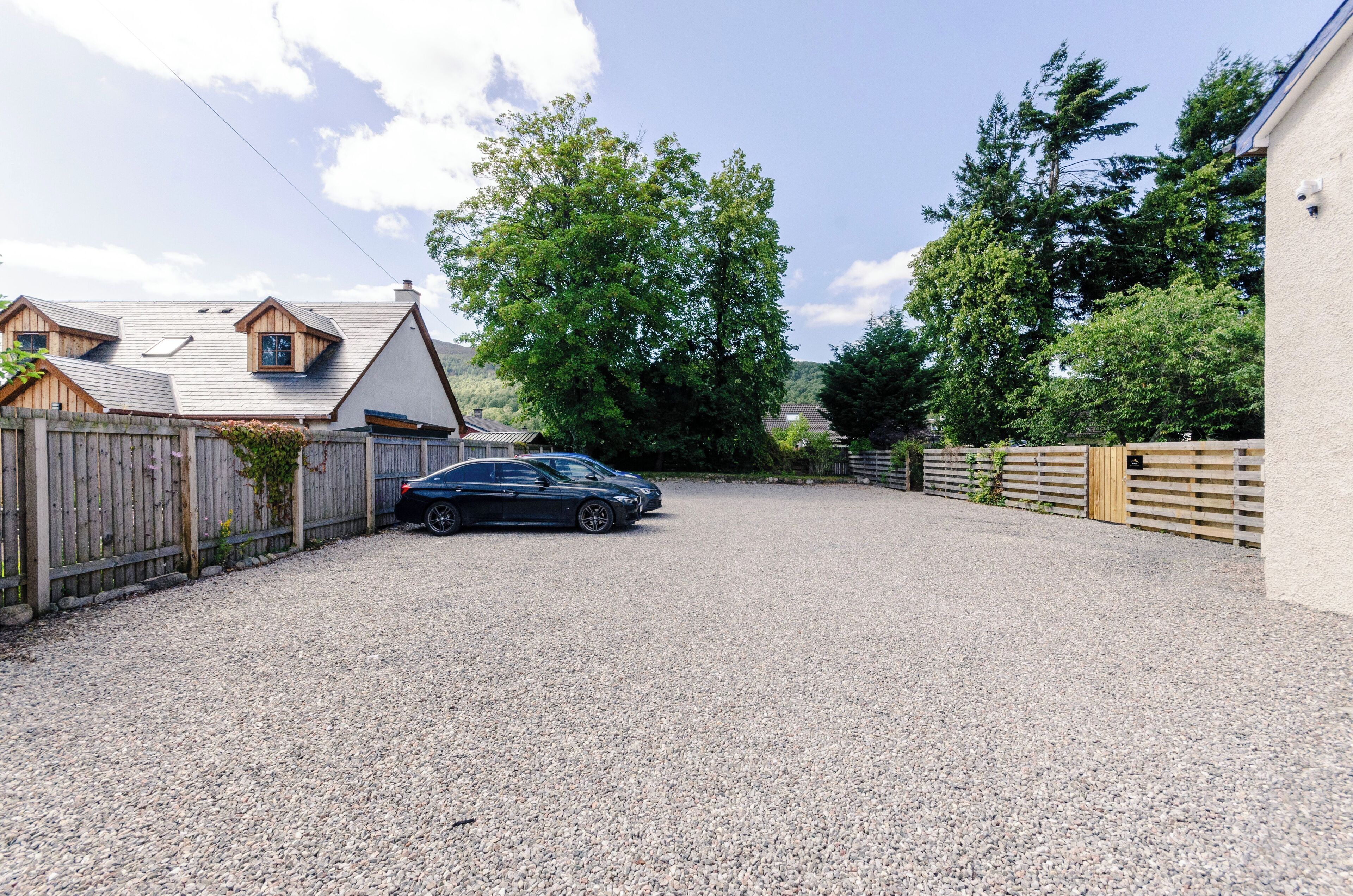 A gravel driveway leading to a house with a car parked in the driveway.