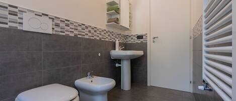 A modern bathroom with a toilet, bidet, and sink.