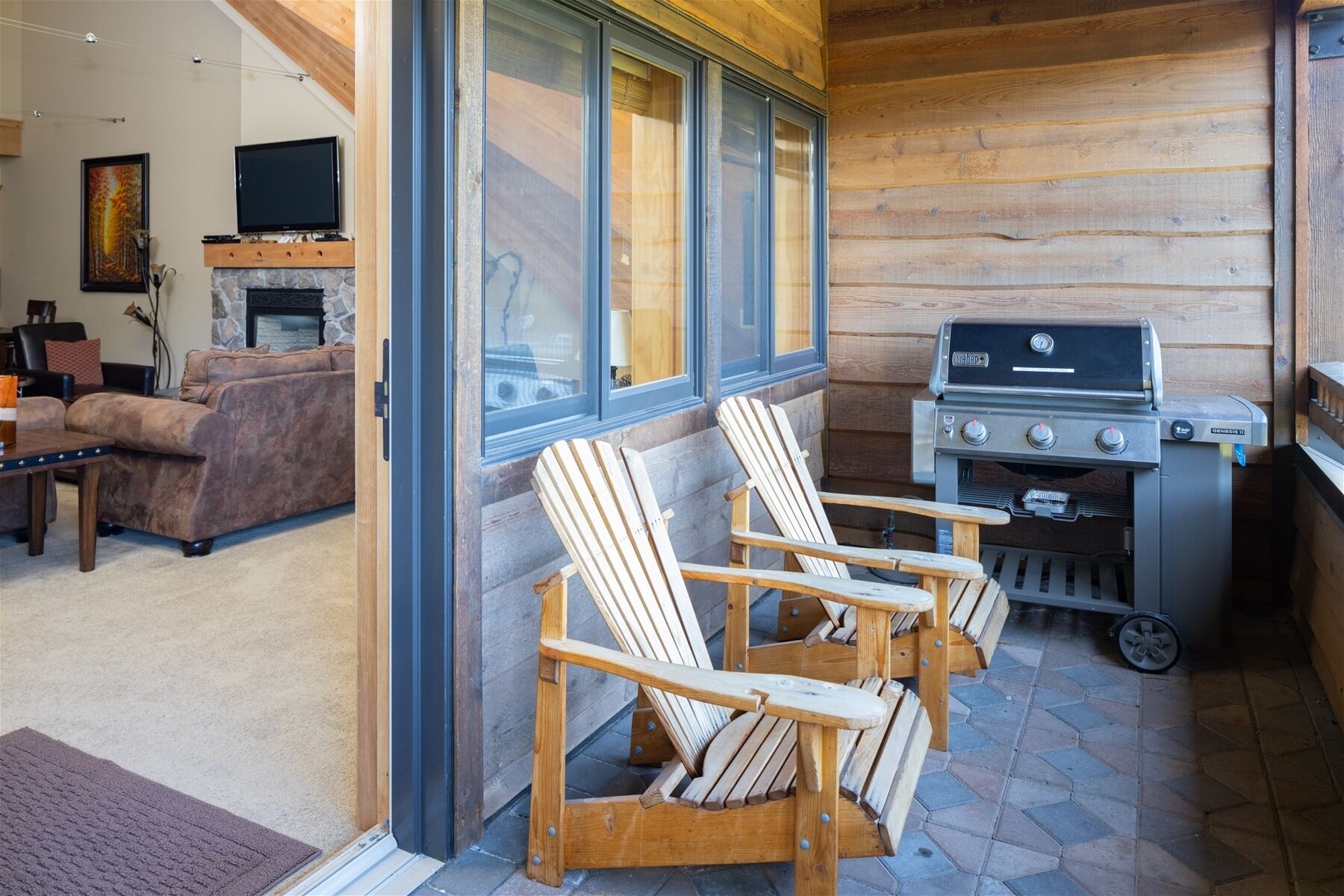 Una sala de estar acogedora con chimenea de piedra, televisión y parrilla.