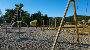 A playground with swings, climbing structures, and a sandpit. - Auberge Alpina (Greolieres)